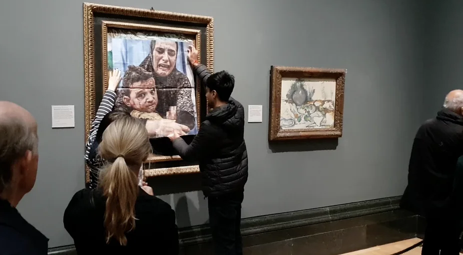 Les deux manifestants de Youth Demand apposent une photo sur le tableau de Pablo Picasso à la National Gallery de Londres. (Crédit : Courtoisie Youth Demand)